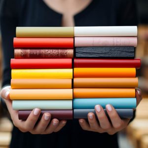 Close up view of hands holding colord cover books stack and a white bricks in background